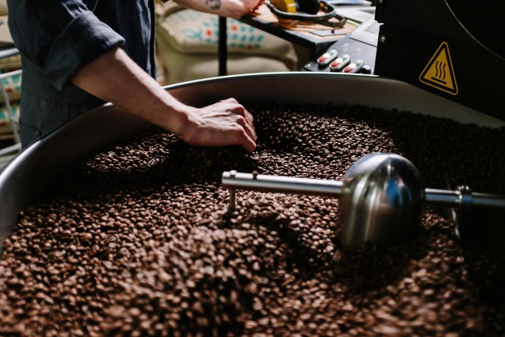 Close-up of a professional roasting coffee beans in an industrial setting, focusing on equipment and beans.